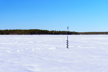 ice drill in the snow on a winter lake. winter sports winter fishing. space for copying text