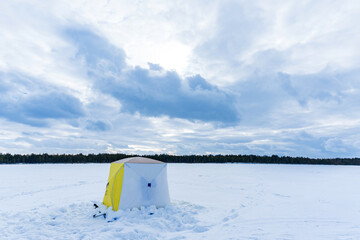 tent camping on ice of the river during ice fishing. Ice fishing adventures concept in winter time. Snow season