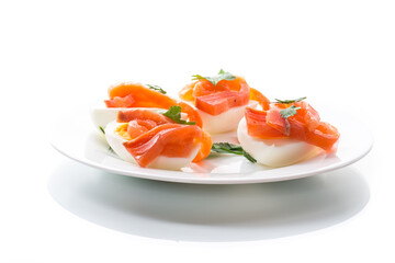halves of boiled eggs with pieces of salted salmon on white background