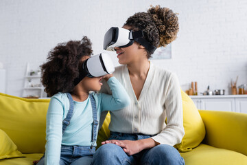 astonished african american kid and smiling woman gaming in vr headsets at home