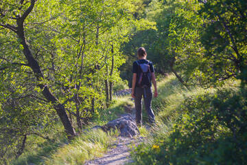 Rearview of a woman hiker with backpacks walking in the Mountain path