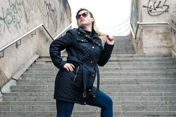 Atractive young woman posing near Waterloo bridge in London in a windy and cloudy day. Sunglasses.