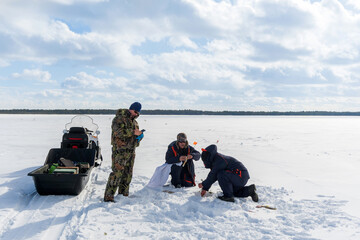 Fishermen on the winter lake check fishing rods for pike fishing. winter fishing