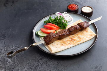 Beef shashlik on a skewer in a plate.