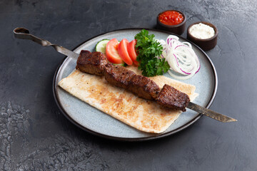 Beef shashlik on a skewer in a plate.