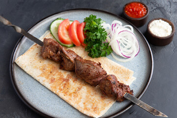 Lamb shashlik on a skewer in a plate.