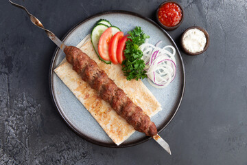 Kebab on a skewer in a plate.