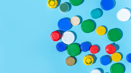 Colorful plastic bottle caps on a blue background, collecting plastic for recycling and reuse. copy space