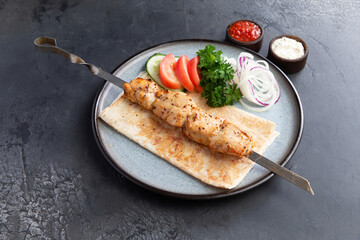 Chicken kebab on a skewer in a plate.