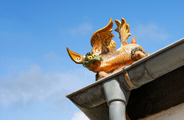 Cute gutter figure on a house against a blue sky