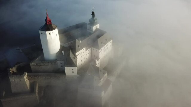 Cinematic aerial drone footage of the charming historical quaint old medieval European Burg Forchtenstein Castle wrapped in morning fog in Burgenland Austria
