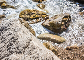 The waves breaking on a stony beach, forming a spray. Close up