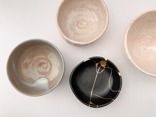Black kintsugi bowl with gold scars, the beauty of being different. Gold scars and Japanese raku pottery