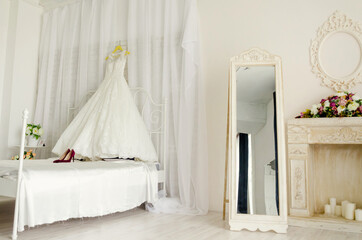 Fototapeta na wymiar White room with bed, wedding dress and mirror, hotel room, studio.