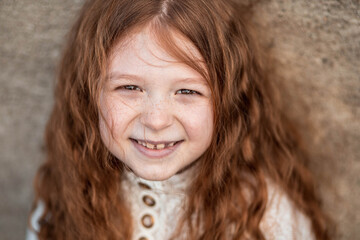 Portrait of a cute, little, ginger girl in white dress