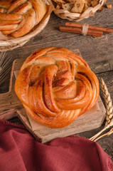 Fresh baked goods - delicious wicker bun with cinnamon on a wooden