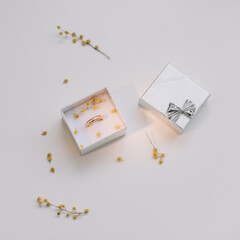 Box with golden engagement ring on flowers background, top view. Wedding, Marriage proposal concept