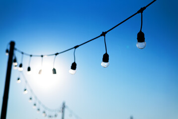 vintage light bulbs on string wire against blue sky in outdoors wedding event party