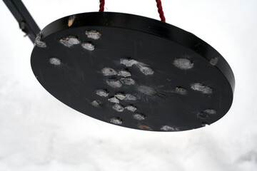 Damaged metal target with bullet marks.