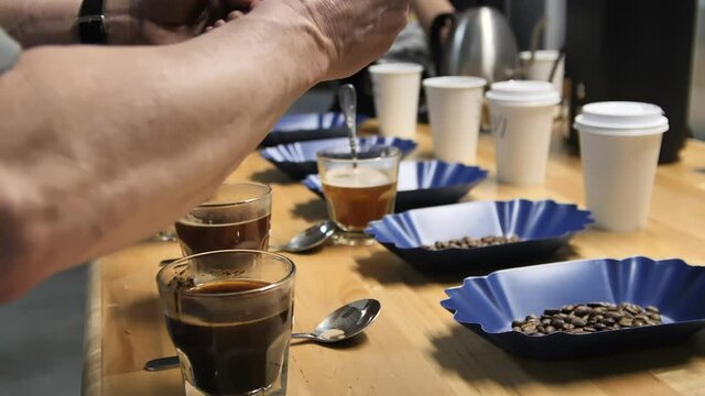 Rinsing spoons during coffee cupping or cup tasting, slow motion close up