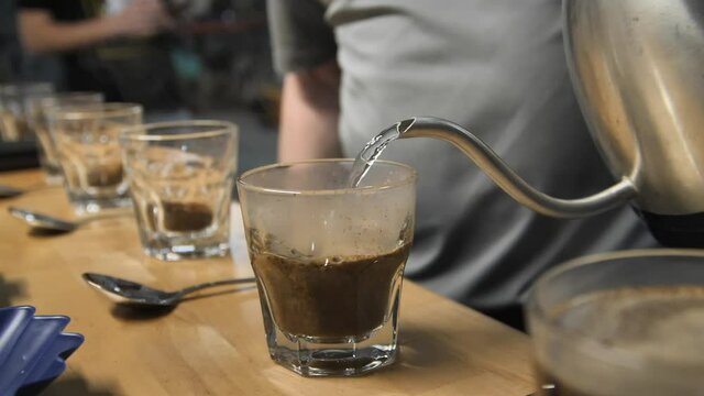 Pouring hot steamy water for coffee cupping taste test, slow motion close up