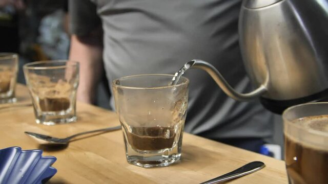 Pouring hot water for coffee cupping taste test, slow motion close up