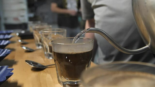 Pour hot steamy water to begin the coffee taste test, slow motion close up