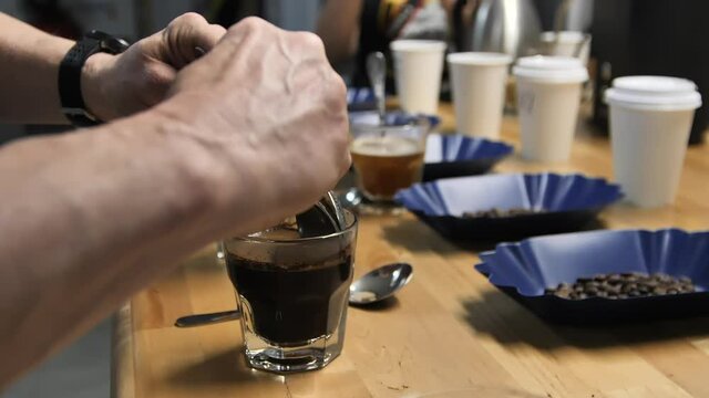 Scraping top layer during coffee cupping using two spoons, slow motion close up