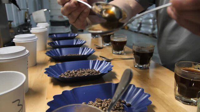 Spoons being rinsed during the coffee cupping test process, slow motion close up