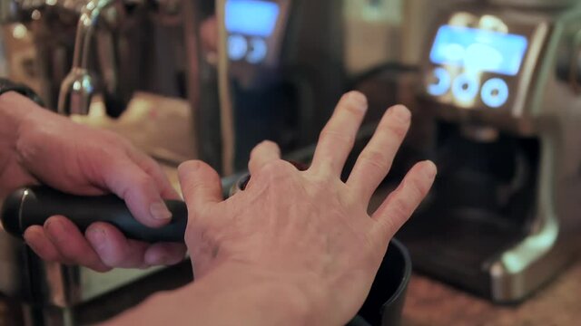 Scraping off excess espresso powder on a portafilter, slow motion close up