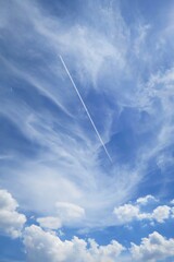 Naklejka na ściany i meble Clear blue sky with white clouds and contrail in summer time. Nature background concept.
