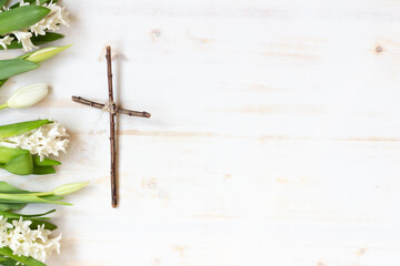 Border of white hyacinth and tulip flowers with wood cross and copy space on white background