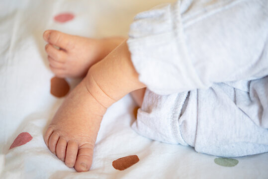 close-up of legs and feet of newborn baby resting on bed