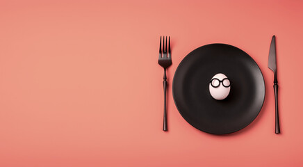 White egg with glasses on a black plate, a table knife and a fork on a pink background. Easter holiday creative concept. Flat lay. Banner. Copy space