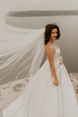 bride woman with short haircut in white wedding corset dress strapless and with a long chiffon veil...