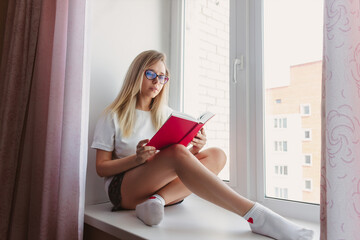 A young blonde beautiful woman Introvert in the white t-shirt and grey shorts with glasses is...