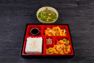 Fototapeta na wymiar Lunch box with seafood, vegetables and chicken soup with greens
