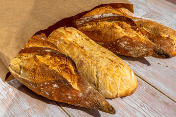 French traditional baguettes in paper bags on wooden table background.