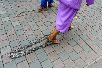 Cucurucho penitent walking barefoot with chains on the Good Friday Easter procession, Quito, Ecuador.