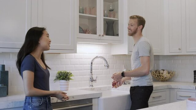 Happy couple talking and playing with an apple in the kitchen