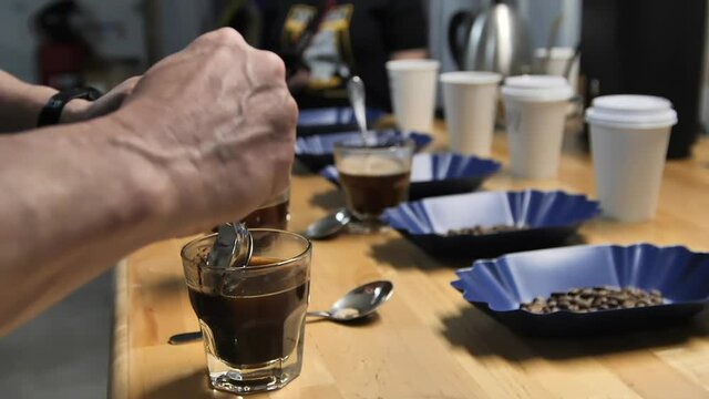 A Master Taster using coffee cupping to test quality, slow motion close up