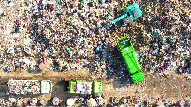 Aerial top view of A Huge Waste, garbage, dump, rubbish landfill. A landfill compactor, group of workers sort out the garbage in the landfill. Trash trucks dump waste polluting products.