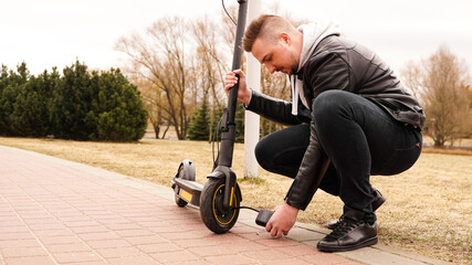 A man pumps air into the wheel of an electric scooter using a special device.