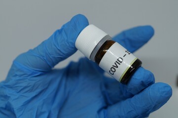 a hand of a doctor with blue gloves holding a covid vaccine 