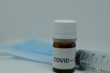 a vaccine for the covid pandemic, a syringe and a blue mask 