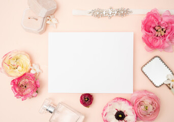 Feminine bridal flat lay with fresh ranunculus flowers, blank greeting card velvet ring box andmirror