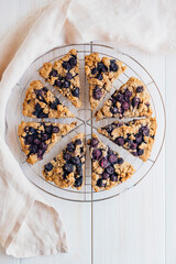 Freshly baked oat blueberry scones on cooling rack on white wooden background. Sweet food with...