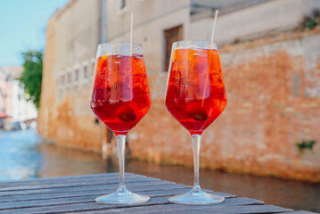 Two glasses of Spritz Veneziano cocktail served near the Venetian canal.  Popular italian summer aperitif drink. Venice background.