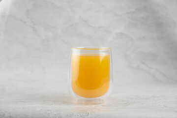 Pineapple juice in double glass cup on white stone background close-up. Isolated