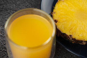Piece of pineapple tropical fruit and yellow juice on dark background